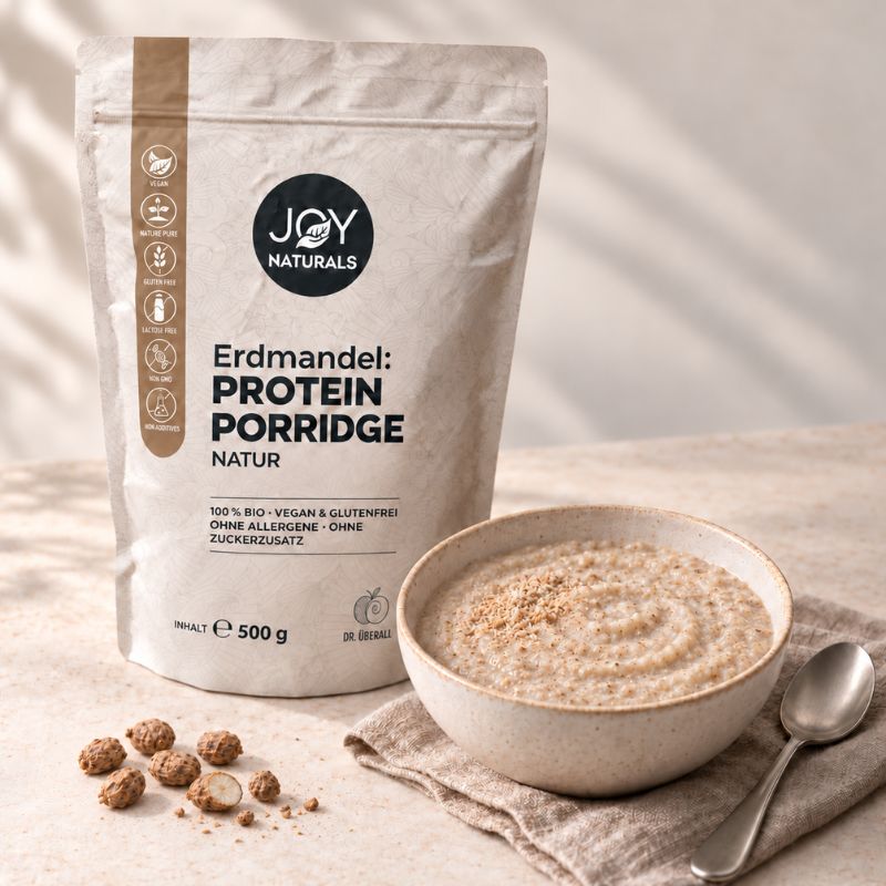 JOY NATURALS Erdmandel Protein Porridge Natur im 500-g-Beutel, daneben eine Schale cremiger Porridge und ganze Erdmandeln.