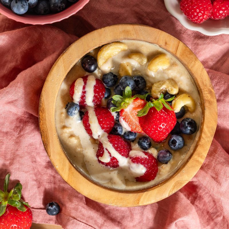 Mandel Protein Porridge Natur von JOY NATURALS, angerichtet mit Früchten und Mandelmus.